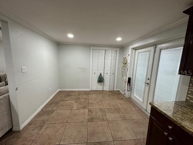 interior space featuring light tile patterned floors and crown molding