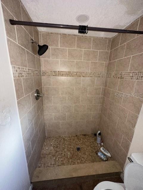 bathroom featuring toilet and tiled shower