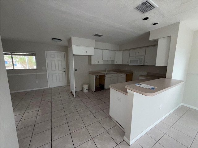 kitchen featuring light tile patterned floors, white cabinetry, kitchen peninsula, and sink