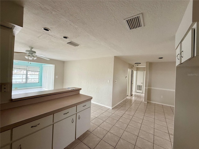 kitchen with a textured ceiling, ceiling fan, light tile patterned flooring, and white cabinets