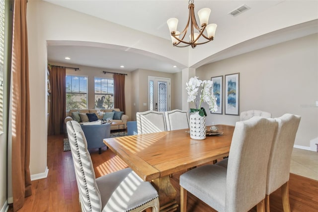 dining area featuring dark wood-type flooring and an inviting chandelier