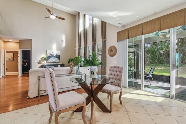 dining area featuring ceiling fan, light tile patterned flooring, and a high ceiling