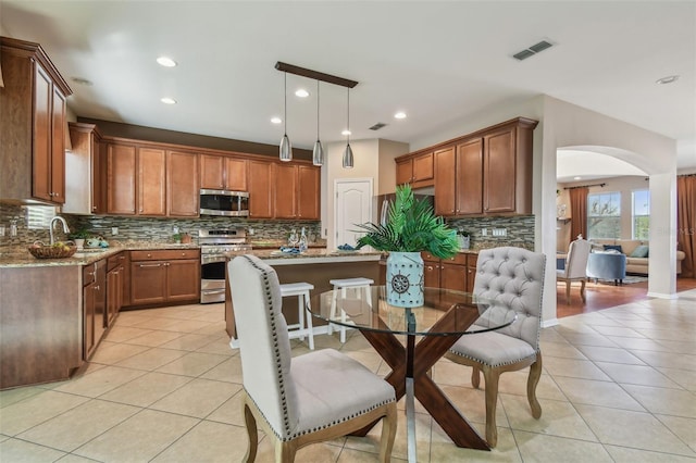 2212 Valterra Vista Way, Valrico, FL 33594 - kitchen featuring stainless steel appliances, arched walkways, light tile patterned floors, backsplash, and recessed lighting