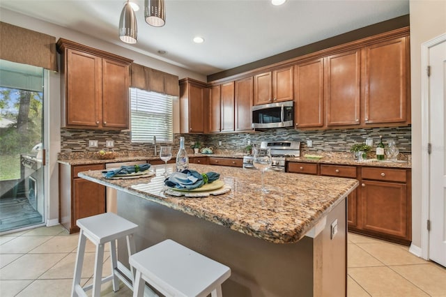 kitchen with appliances with stainless steel finishes, a kitchen breakfast bar, a kitchen island with sink, and pendant lighting