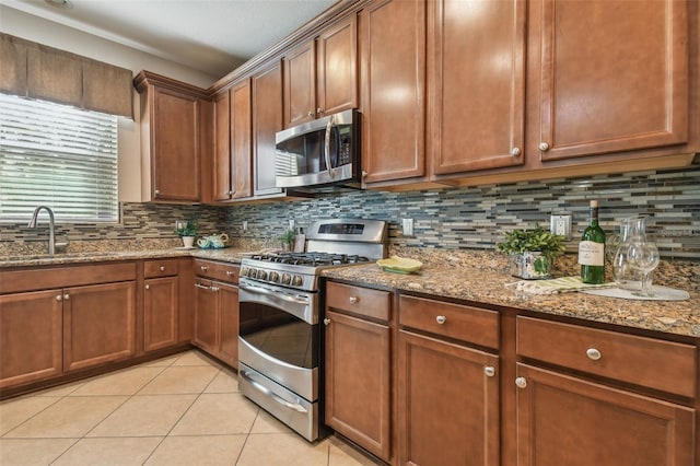 kitchen with sink, light stone countertops, stainless steel appliances, and light tile patterned floors