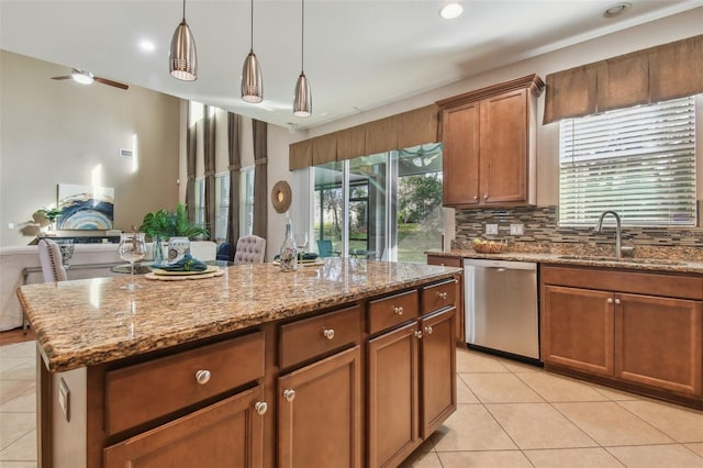 kitchen featuring stainless steel dishwasher, sink, light tile patterned floors, decorative light fixtures, and a center island