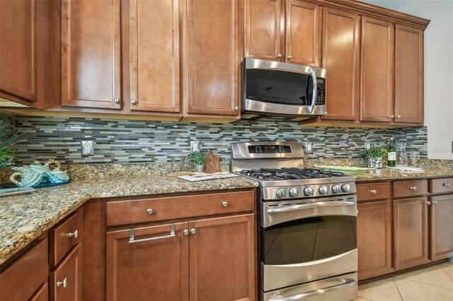 2212 Valterra Vista Way, Valrico, FL 33594 - kitchen featuring appliances with stainless steel finishes, light tile patterned flooring, backsplash, and light stone countertops