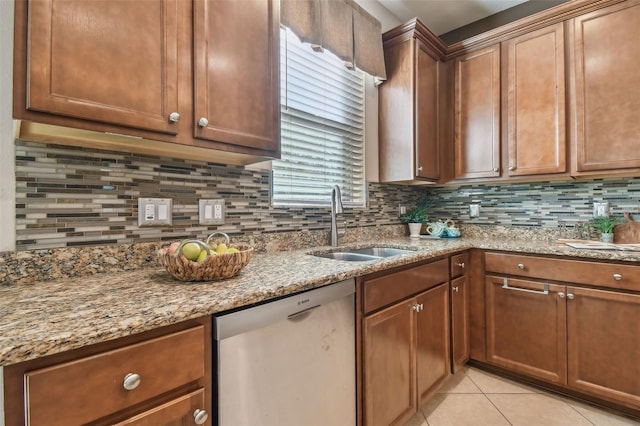 kitchen featuring light stone countertops, sink, stainless steel dishwasher, backsplash, and light tile patterned floors