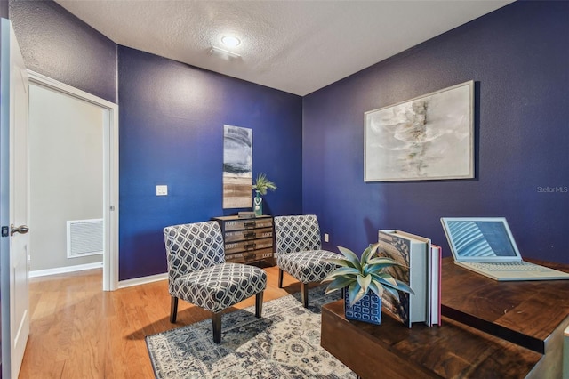 sitting room with hardwood / wood-style floors and a textured ceiling