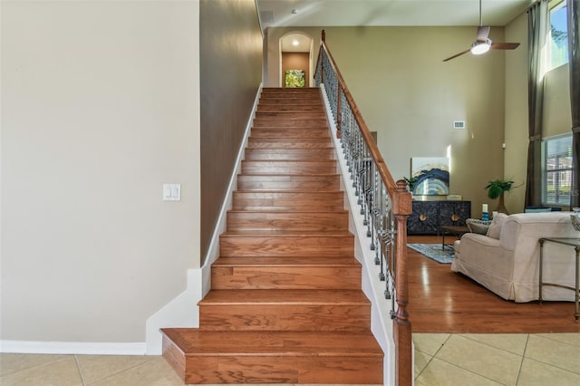 stairs featuring a high ceiling, tile patterned floors, ceiling fan, and a healthy amount of sunlight