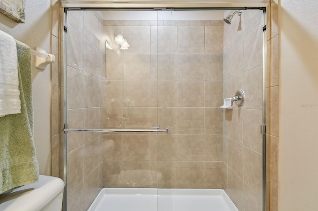 bathroom featuring toilet and a shower with shower door