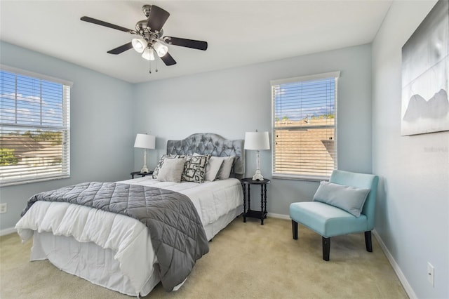 bedroom with multiple windows, ceiling fan, and light carpet