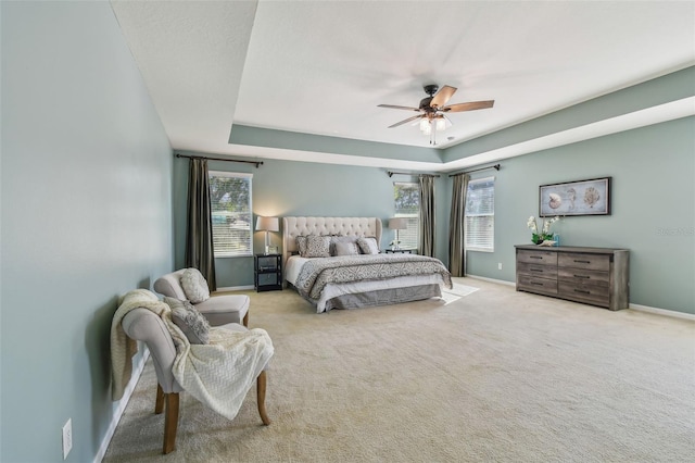 bedroom featuring light colored carpet, ceiling fan, and a tray ceiling