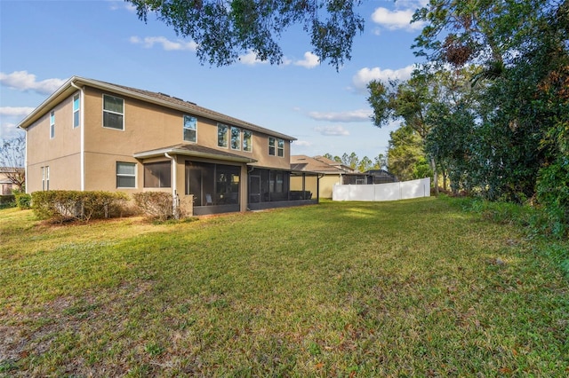 rear view of property featuring a sunroom and a yard