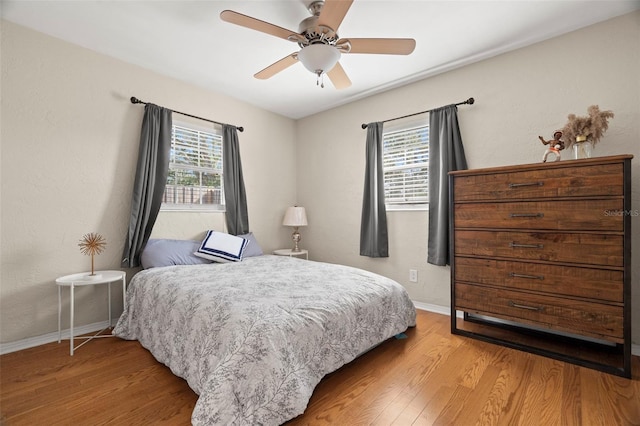 bedroom featuring multiple windows, hardwood / wood-style flooring, and ceiling fan