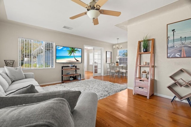 living room with hardwood / wood-style floors and ceiling fan with notable chandelier