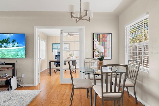 dining space with ceiling fan with notable chandelier and light wood-type flooring