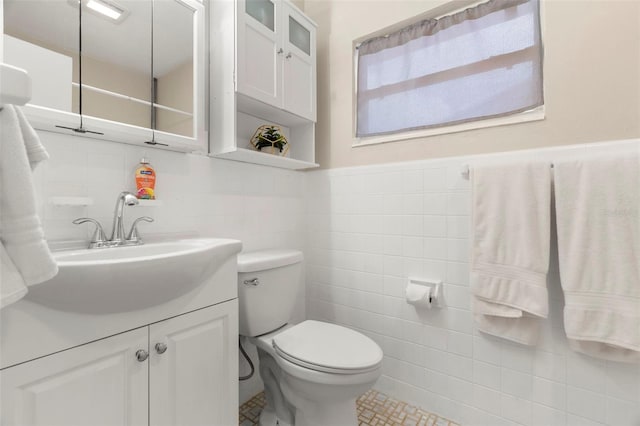 bathroom featuring vanity, tile walls, and toilet