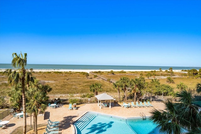 view of pool with a water view and a beach view