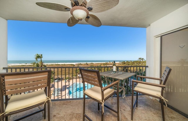 balcony with ceiling fan, a water view, and a beach view