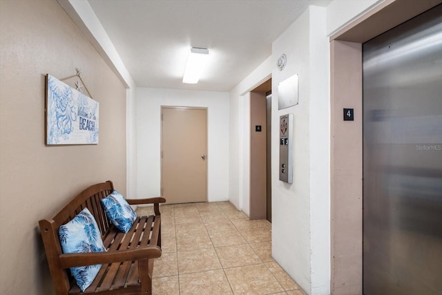 hall featuring light tile patterned floors and elevator