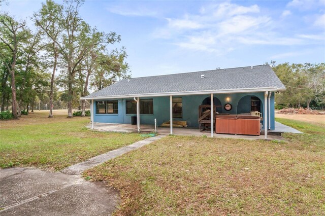 exterior space featuring a front lawn, a patio, and a hot tub