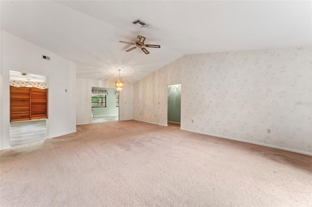 unfurnished living room featuring ceiling fan with notable chandelier, carpet floors, and lofted ceiling