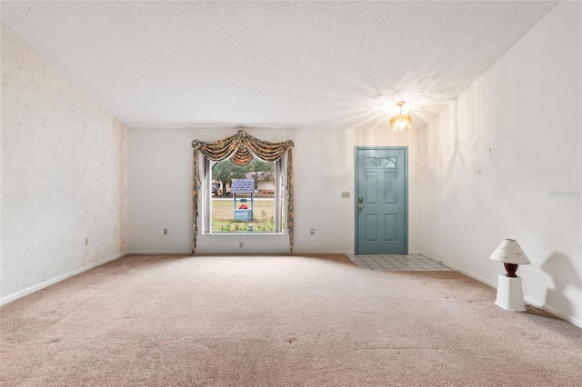 empty room with carpet, a textured ceiling, and a chandelier