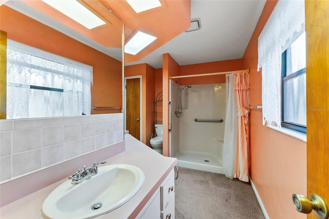 bathroom featuring vanity, toilet, walk in shower, and a healthy amount of sunlight