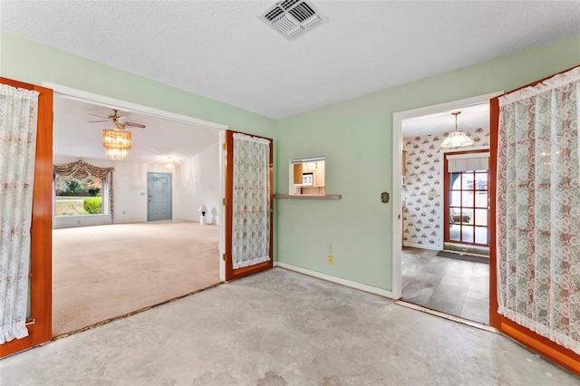 carpeted spare room with ceiling fan, a textured ceiling, and a wealth of natural light