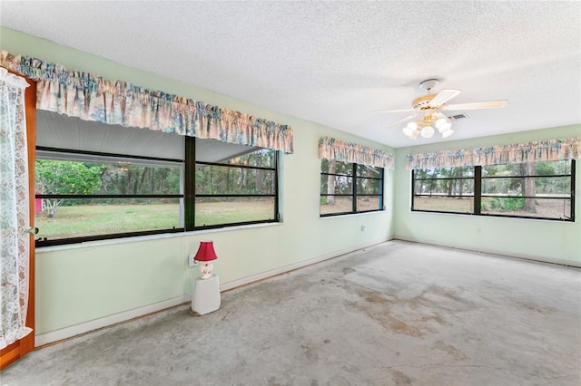 spare room with ceiling fan, a textured ceiling, and concrete floors