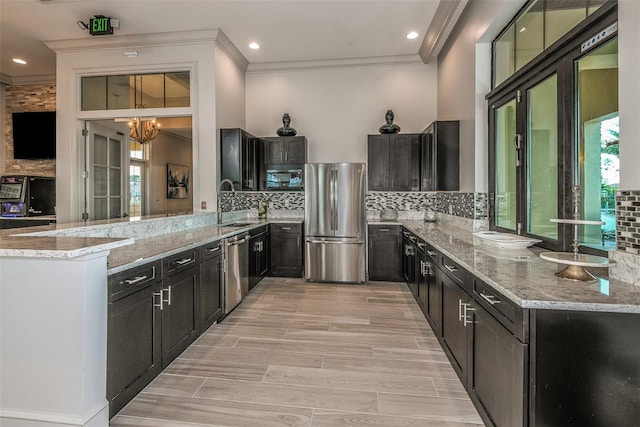 kitchen with appliances with stainless steel finishes, tasteful backsplash, a wealth of natural light, and a notable chandelier