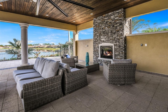 view of patio featuring an outdoor living space with a fireplace, ceiling fan, and a water view