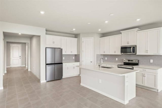 kitchen with appliances with stainless steel finishes, a sink, backsplash, light countertops, and white cabinets