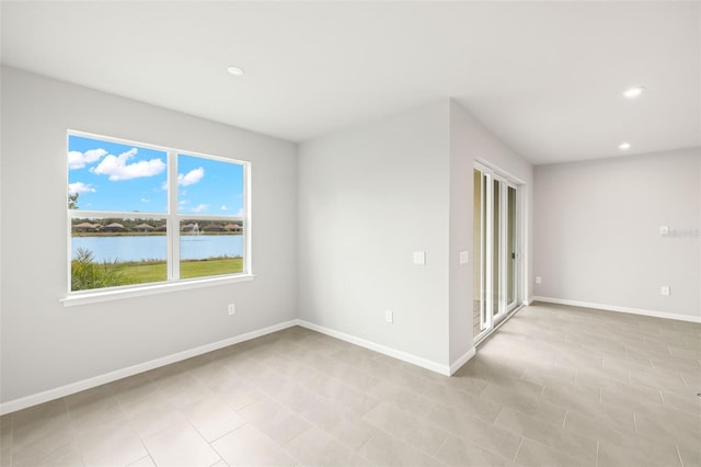 spare room with recessed lighting, baseboards, and a water view