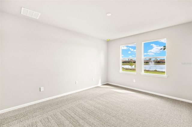carpeted empty room featuring baseboards and a water view