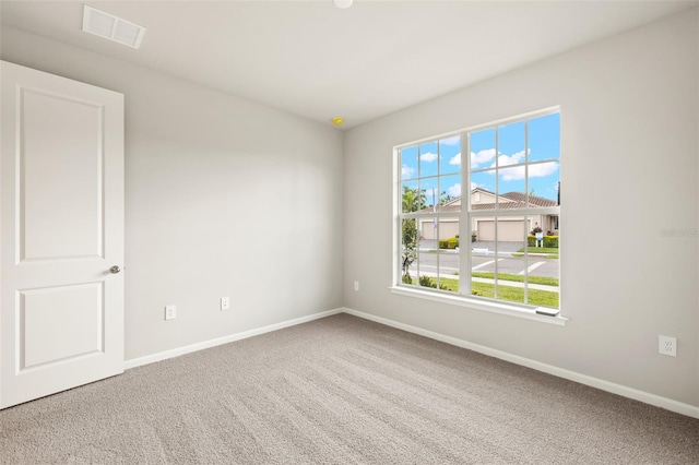 carpeted spare room featuring plenty of natural light and baseboards