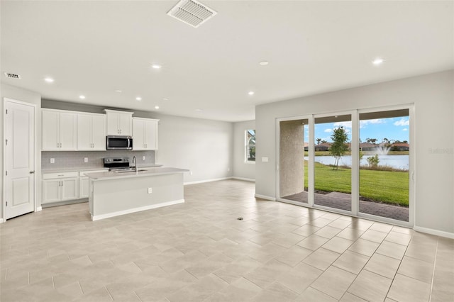 kitchen with stainless steel appliances, light countertops, a water view, tasteful backsplash, and recessed lighting