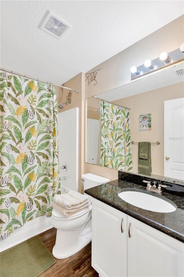 full bathroom with a textured ceiling, vanity, hardwood / wood-style flooring, shower / bathtub combination with curtain, and toilet