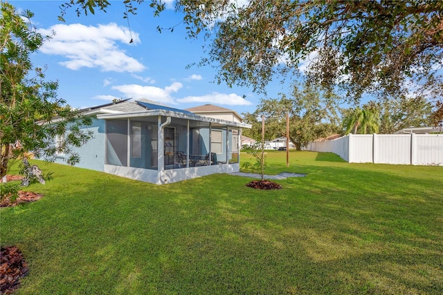 rear view of house with a lawn and a sunroom