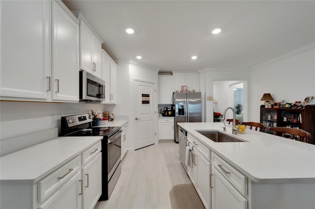 kitchen featuring stainless steel appliances, a center island with sink, crown molding, white cabinets, and sink