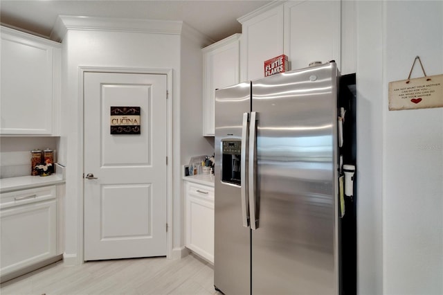 kitchen with white cabinets, ornamental molding, and stainless steel refrigerator with ice dispenser