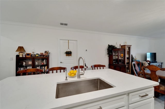 kitchen with sink, a breakfast bar, white cabinetry, and crown molding