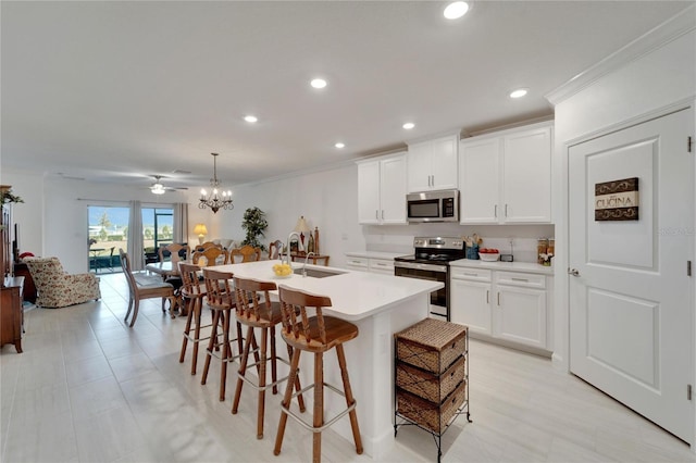 kitchen featuring decorative light fixtures, stainless steel appliances, an island with sink, and sink