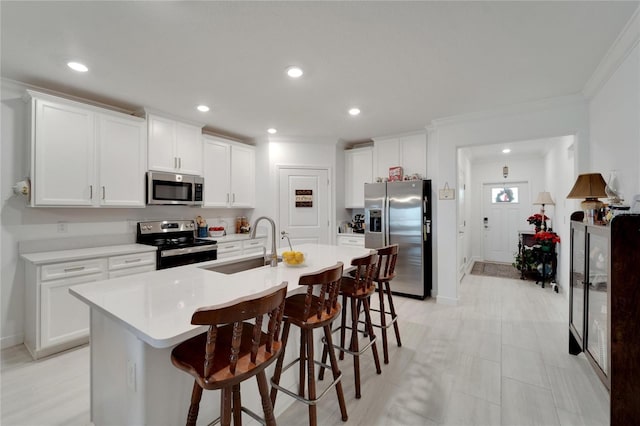 kitchen featuring stainless steel appliances, an island with sink, a breakfast bar area, white cabinetry, and sink