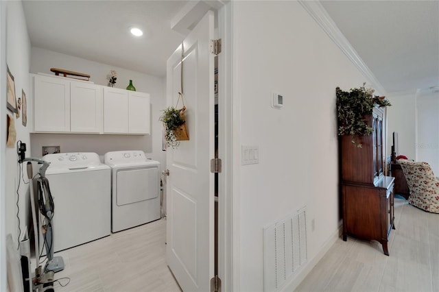 laundry area with cabinets, washer and clothes dryer, and crown molding