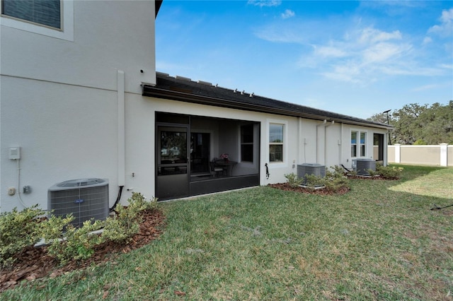 rear view of house with a sunroom, a yard, and central AC unit