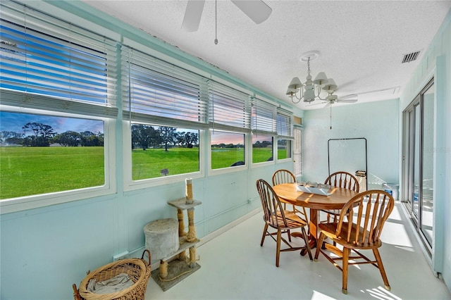 sunroom featuring ceiling fan with notable chandelier