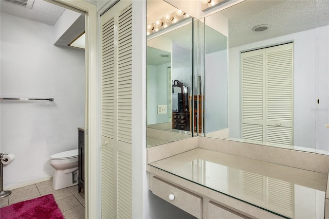 bathroom featuring tile patterned floors, vanity, a textured ceiling, and toilet