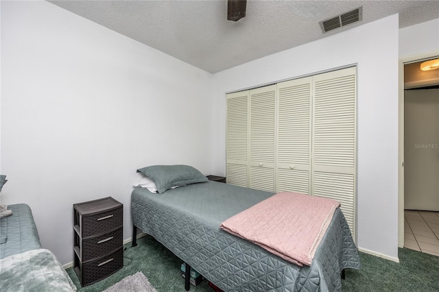 carpeted bedroom featuring ceiling fan, a closet, and a textured ceiling